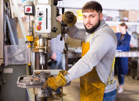 Craftsman working on metal structures drilling machine
