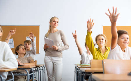 Pupils raising hands during lesson in schoolの写真素材