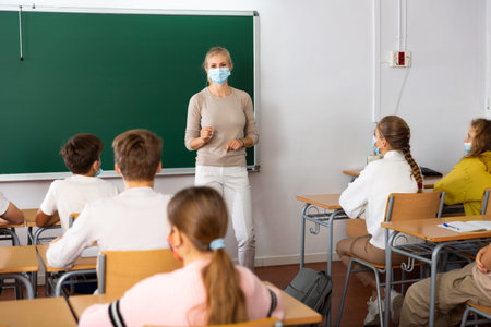 Teacher in mask explaining new theme to children