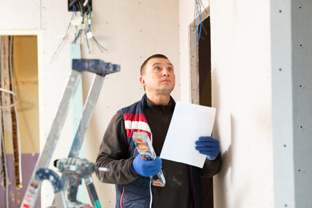 Builder standing at indoors building site, reading document