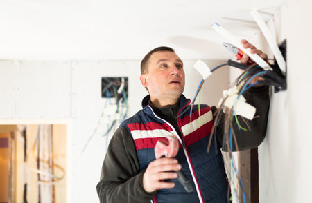 Electrician working with wires in apartment