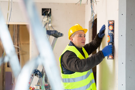 Repair man measuring evenness of wall