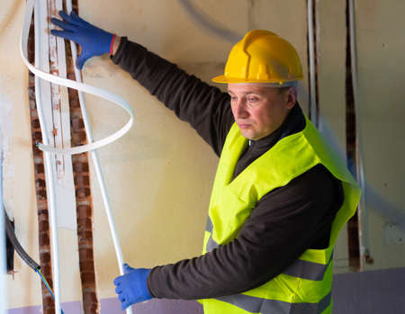 Plumber prepares plastic pipes for installation in building under constructionの写真素材