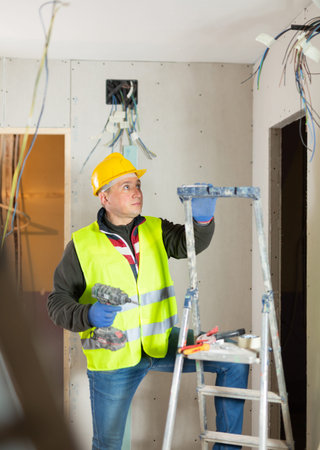 Repair man with drill working in apartment