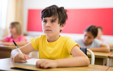 Schoolboy sitting in classroom during lesson in elementary school