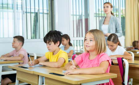 Group of school kids and teacher during lesson in classroomの写真素材
