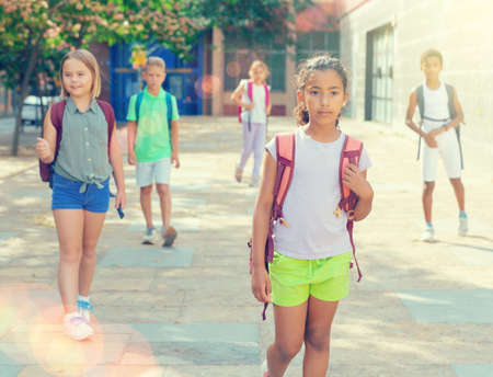 Portrait of smiling schoolgirl walking on street, kids on backgroundの写真素材