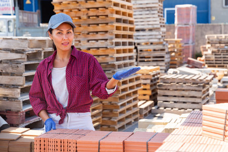 Asian construction shop worker stacks bricks on an open-air site