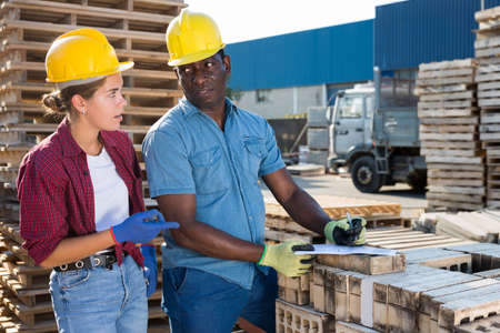 Manager and employee check documents and construction materials at the open-air site of construction storeの写真素材