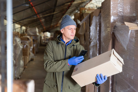 Store worker scans qr code on boxes using smartphone in warehouse shop