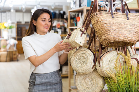 Young woman choosing straw bag at shopの写真素材