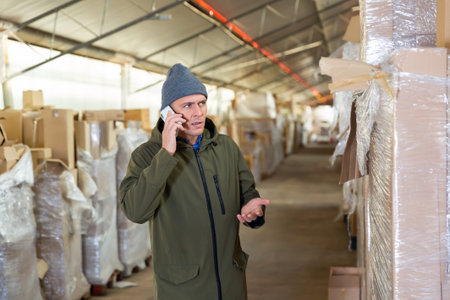 Man in winter clothes talking on mobile phone in warehouseの写真素材