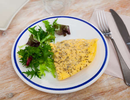 Fluffy omelet seasoned with herbs served with fresh greensの写真素材