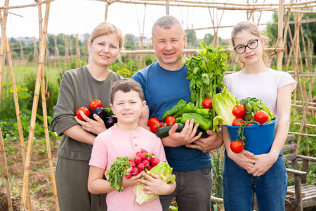 Happy family with fresh harvest in backyard garden