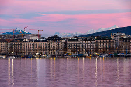 Geneva cityscape seen with lake and snow-capped mountains in background at twilightのeditorial素材