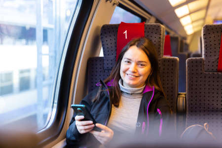 Woman using her smartphone while traveling by trainの写真素材