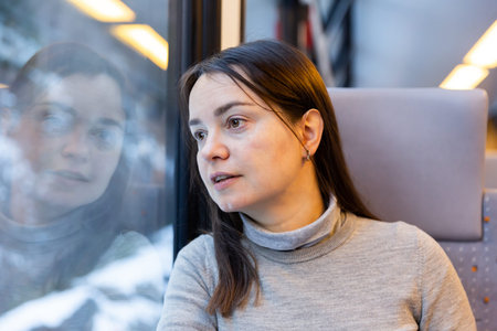 Female traveler looking with interest at scenery outside train window
