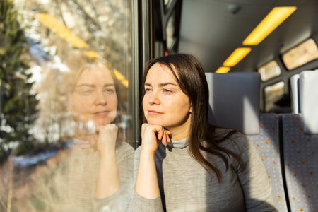 Pensive woman traveler sitting inside train and looking out window