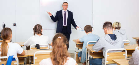 Adult teacher is giving lecture for students in classの写真素材