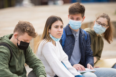 Teenagers in face masks talking outdoorsの写真素材