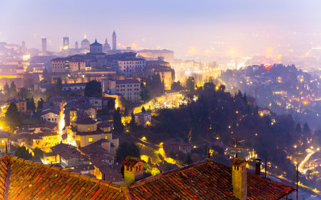 Illuminated Bergamo upper city in misty winter twilights, Italyの写真素材