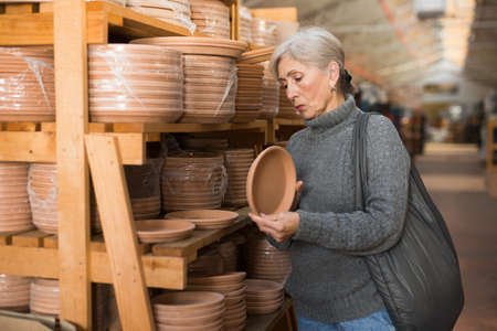 Elderly woman looking for flower pots in hypermarketの写真素材