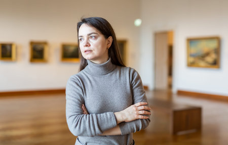 Female art lover viewing collection of paintings in art museum