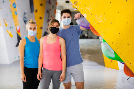 Portrait of women and guy in protective mask in climbing gym