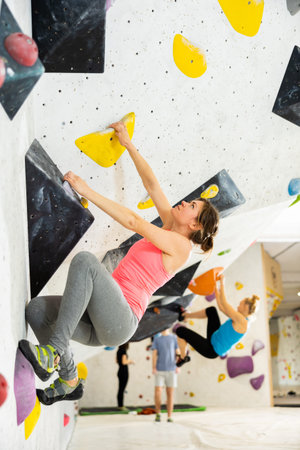 Woman grabbing ledges of artificial climbing wall