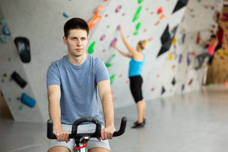 Sports guy on an exercise bike in climbing hallの写真素材