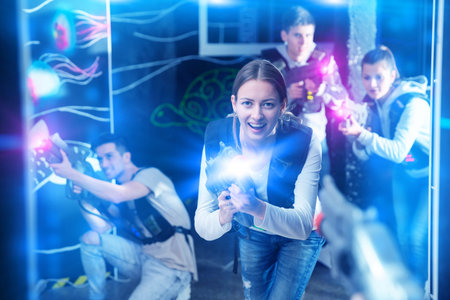 Smiling girl with laser guns took aim and having fun with friends