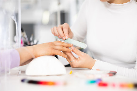 Woman hands, with which the manicure master files nailsの写真素材
