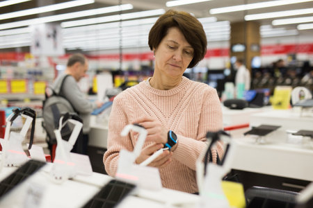 Focused European woman chooses an electronic watchの写真素材