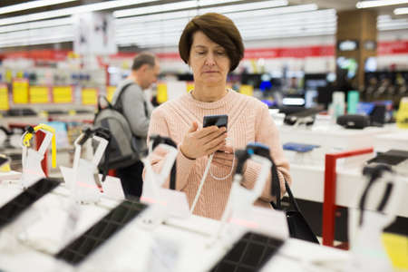 European woman attentive selects a mobile phoneの写真素材