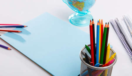 Various color pencils and notebooks on a wooden tableの写真素材