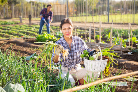 Cheerful asian woman with vegetable harvest in backyard garden
