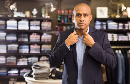 Man choosing suit jacket in clothing store