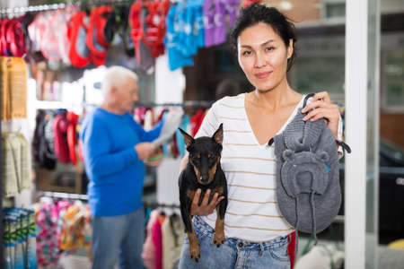 Woman choosing clothing for her dog in pet shopの写真素材
