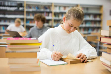 Fourteen-year-old schoolgirl writes out an synopsisの写真素材