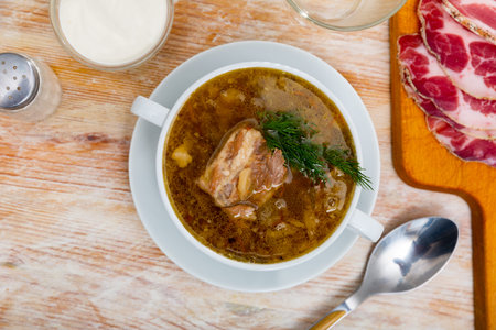 Shchi cooked from sauerkraut with pork meat served with sour cream