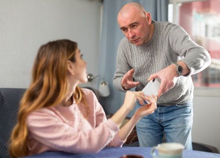 Amazed woman trying to dont give away her phone to her jealous husbandの写真素材