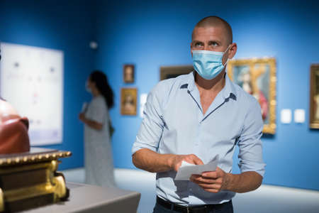 Adult man in face mask standing in galleryの写真素材