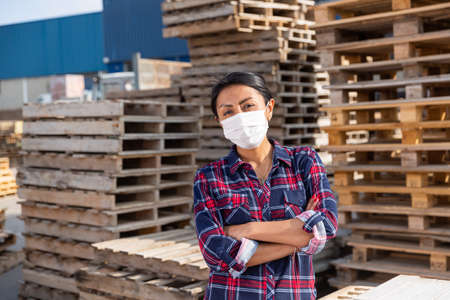 Portrait of woman worker in mask posing at warehouseの写真素材