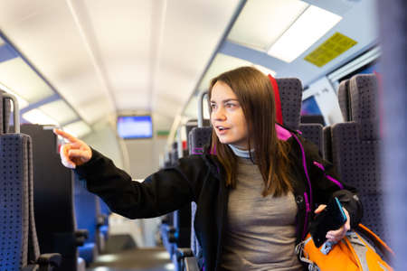 Woman pointing finger at something while traveling by trainの写真素材