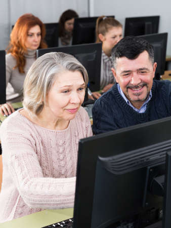 Woman explaining something to man coworker, pointing at computer monitorの写真素材