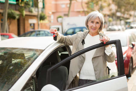 Mature lady standing beside carの写真素材