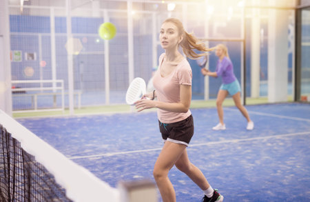 Woman serving ball while playing padel in courtの写真素材