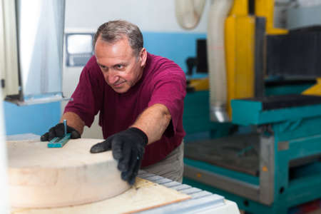 Elderly worker fixes wooden workpiece in 3d machineの写真素材
