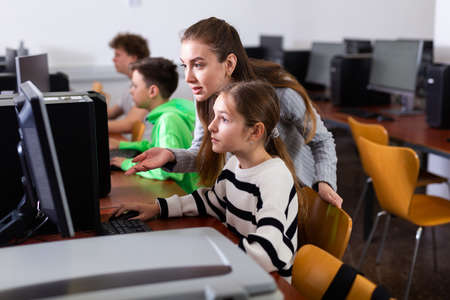 Teacher helping girl to solve computer problemの写真素材