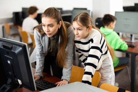 Female teacher consulting teenage girl studying in information technology classの写真素材